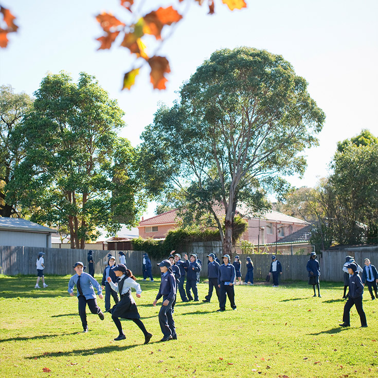 Older photo of students running on Sacred Heart Catholic Primary School Westmead lawn